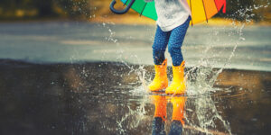 child with yellow rubber boots stomping in rain
